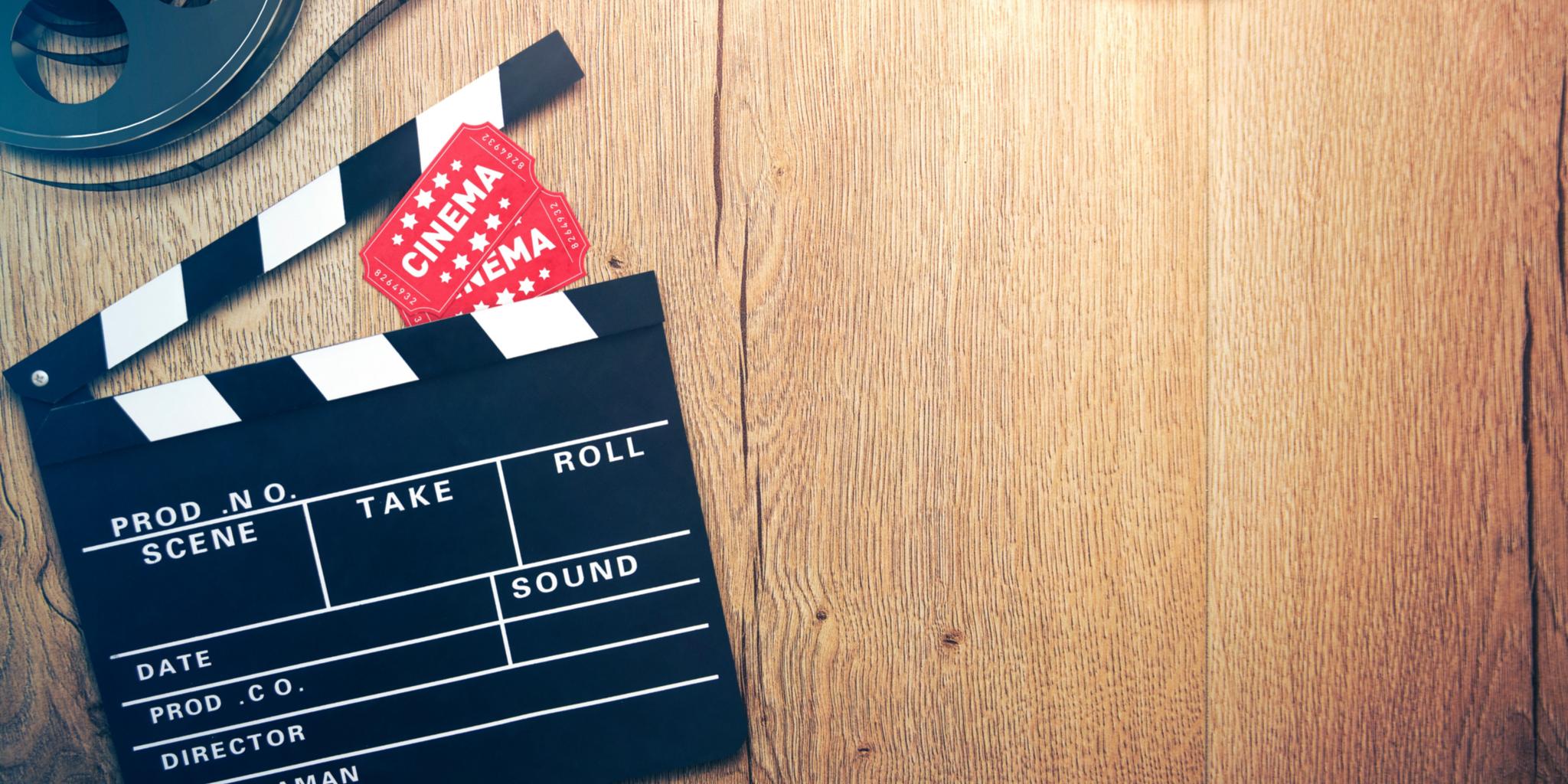Eine Filmrolle und Regieklappe liegen auf einem Holzboden