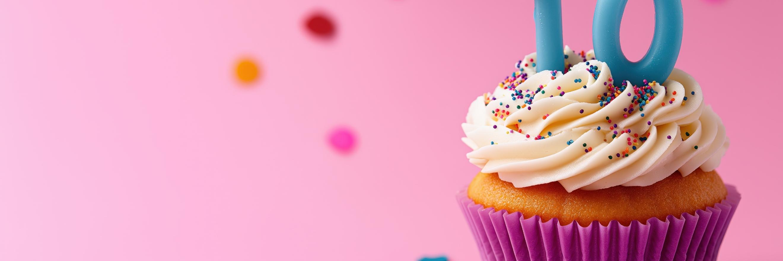 Ein Muffin mit Zahlenkerzen zehn vor rosa Hintergrund