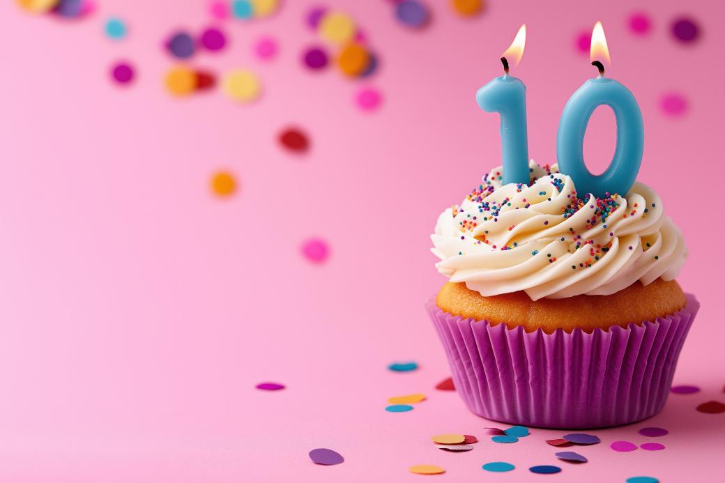 Ein Muffin mit Zahlenkerzen zehn vor rosa Hintergrund