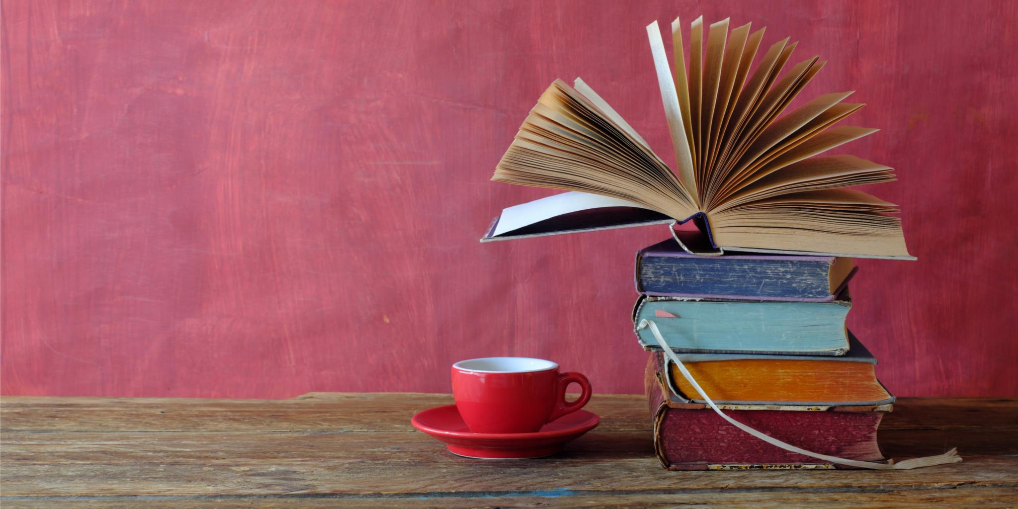 Ein Bücherstapel auf einem Tisch und eine Tasse Kaffee