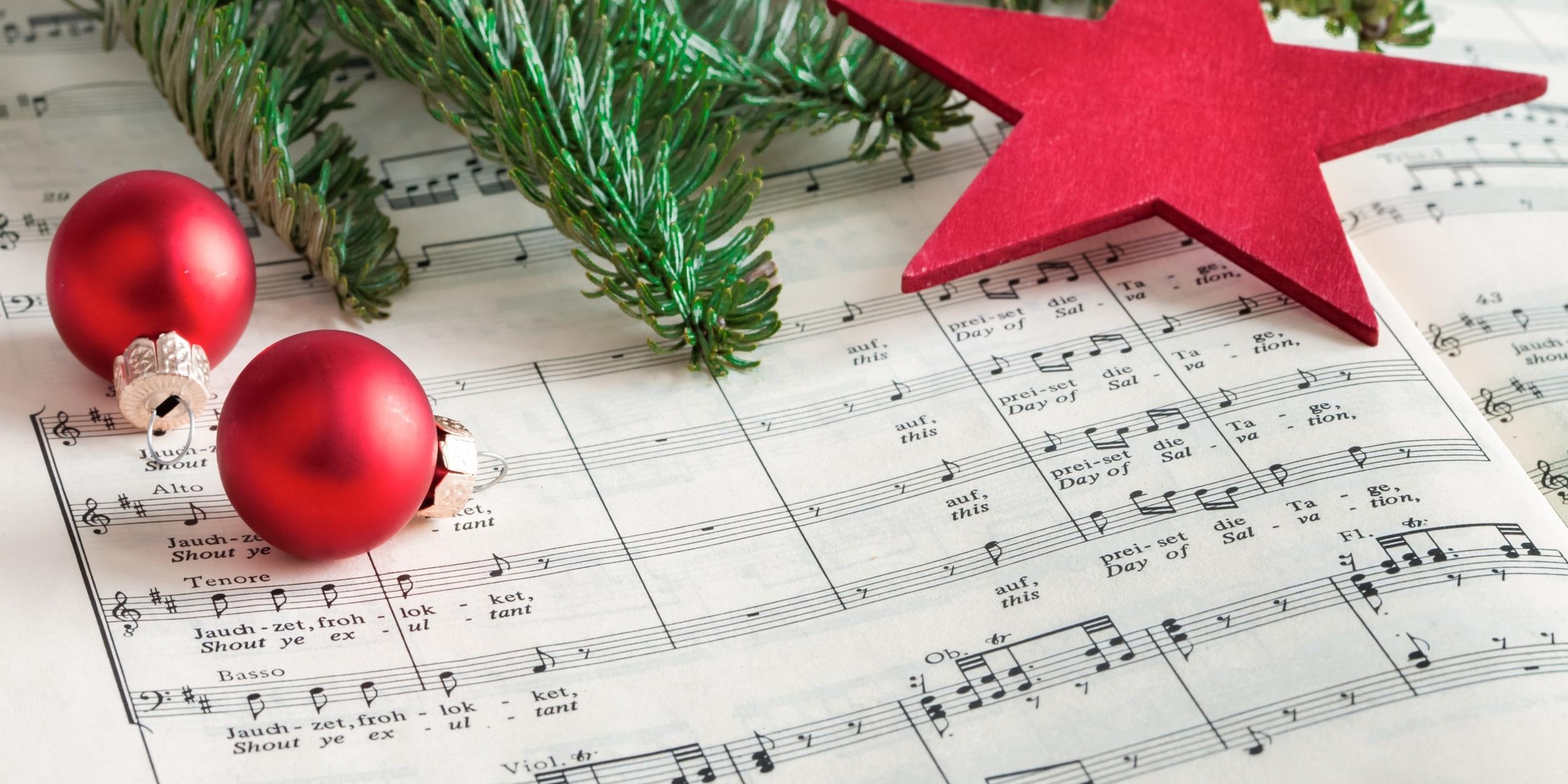 Ein Notenblatt, auf dem Christbaumkugeln, ein Tannenzweig und ein Stern liegen
